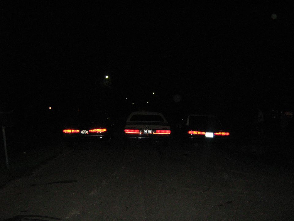 three cars parked at night, taillights on