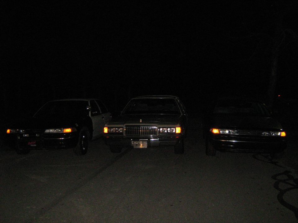 Three cars parked at night, a 1988 Mercury Grand Marquis in the center with two other sedans on either side