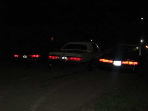 1988 Mercury Grand Marquis - Three cars are parked at night, with the middle vehicle appearing to be a 1988 Mercury Grand Marquis.