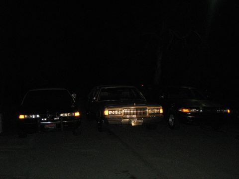 1988 Mercury Grand Marquis - Three sedans parked at night. The middle car is a 1988 Mercury Grand Marquis.