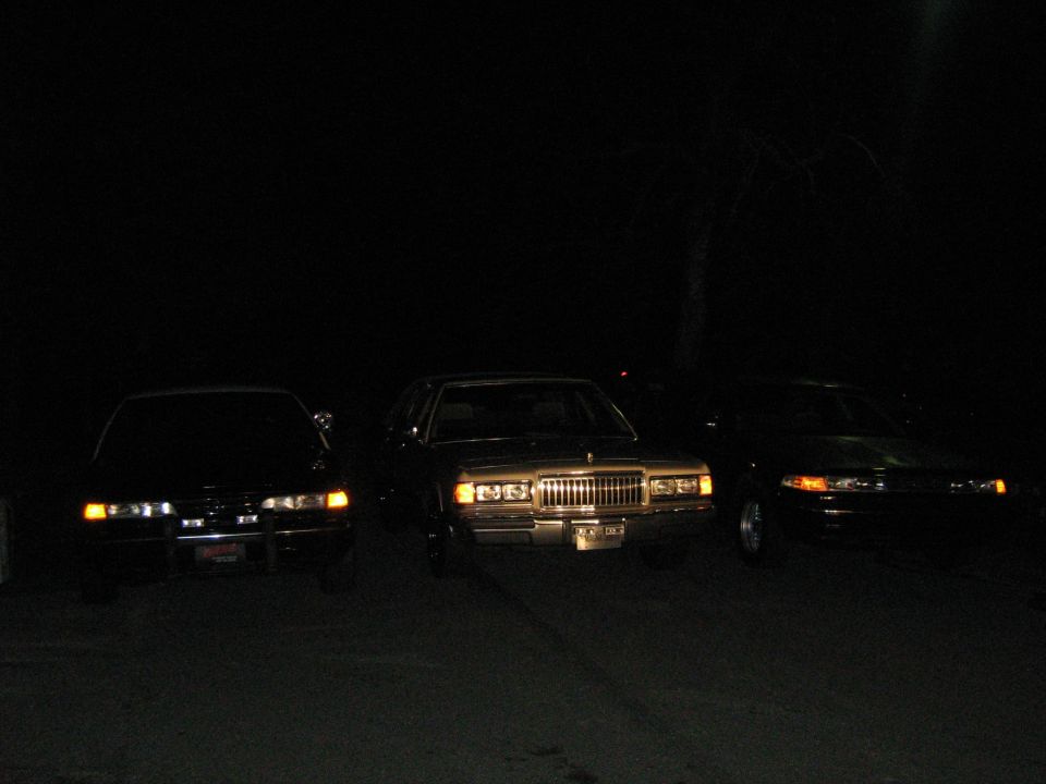 Three sedans parked at night, one is a 1988 Mercury Grand Marquis