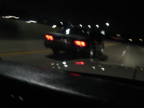 1988 Mercury Grand Marquis - A 1988 Mercury Grand Marquis is seen from behind while driving on a road at night.