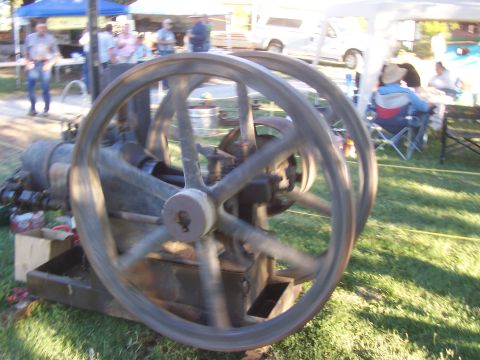1994 Ford F-150 - An old engine with large flywheels is displayed outdoors, with a crowd and tents visible in the background.