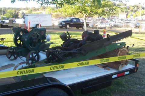 1994 Ford F-150 - Antique logging equipment is transported on a trailer, with a black pickup truck visible in the background.