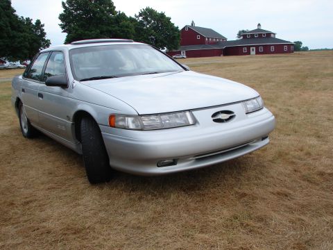 1993 Ford Taurus - Silver 1993 Ford Taurus sits in a field with barns behind it.