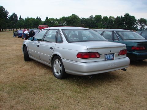 1993 Ford Taurus - A silver 1993 Ford Taurus is parked on a grassy field next to other vehicles.