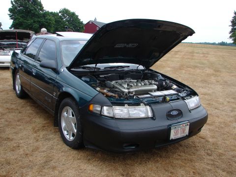 1993 Ford Taurus - 1993 Ford Taurus SHO at a car show, engine exposed. Another vehicle is parked nearby.