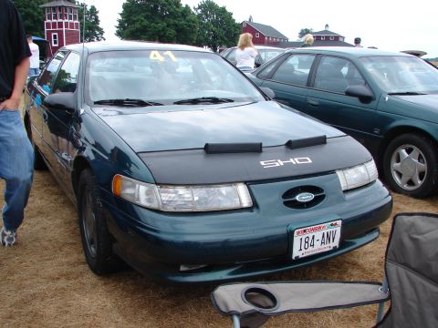 1993 Ford Taurus - A dark green 1993 Ford Taurus SHO is parked at a car show, identified by the SHO bra and windshield number.