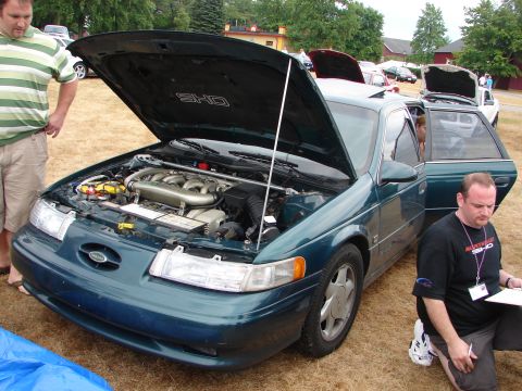 1993 Ford Taurus - A 1993 Ford Taurus SHO is displayed with its hood open, revealing the engine compartment.
