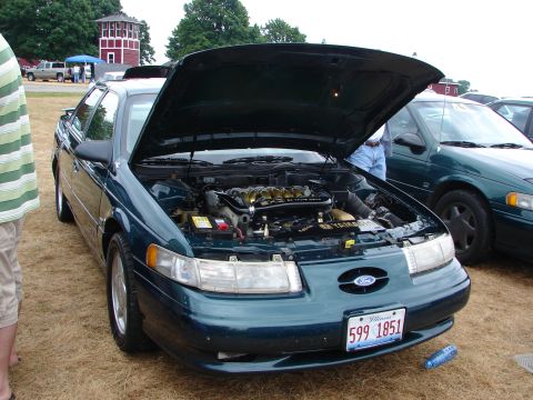 1993 Ford Taurus - A dark green 1993 Ford Taurus is displayed with its hood open, revealing the engine bay.
