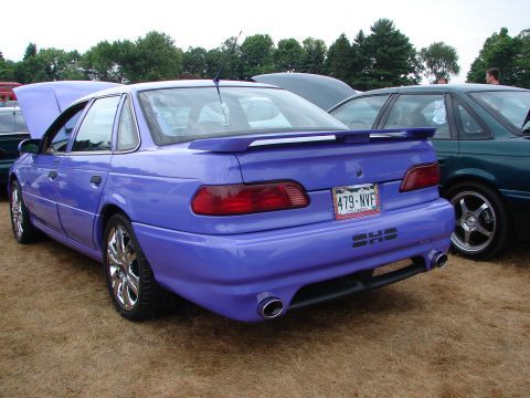 1993 Ford Taurus - A modified purple sedan is parked on a grassy lot next to another vehicle.