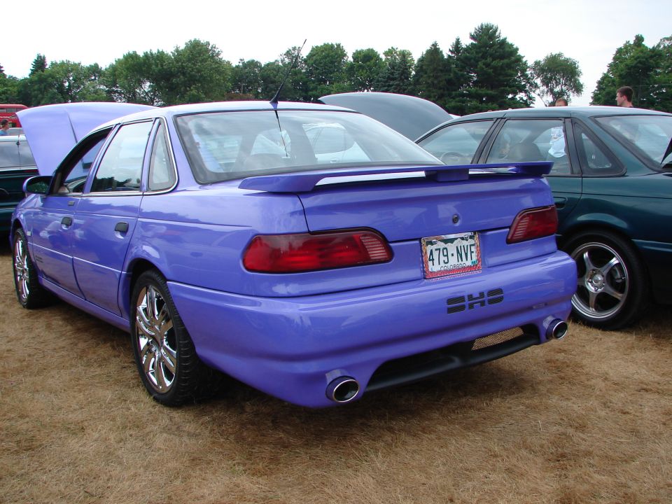 Purple sedan with custom body kit and spoiler, parked next to another car