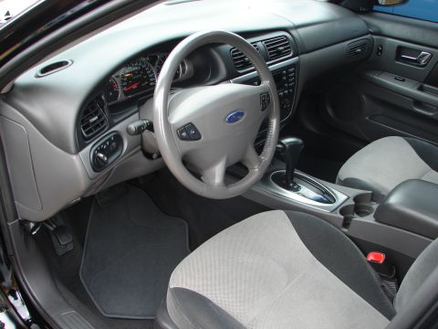 1993 Ford Taurus - The interior of a car features a dashboard with gauges, a steering wheel, and two-tone seats.