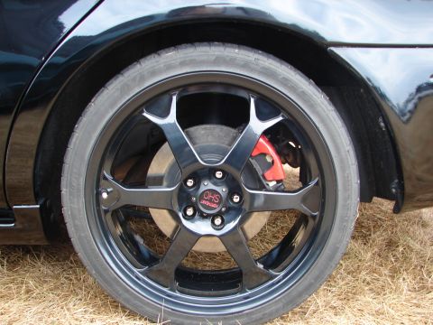 1993 Ford Taurus - Close-up of a black aftermarket wheel with a red brake caliper on a black vehicle.