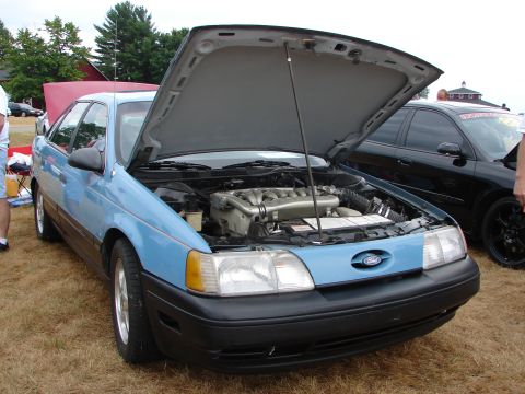 1993 Ford Taurus - A light blue sedan with its hood open reveals the engine bay, parked outdoors.