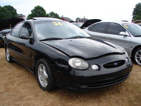 1993 Ford Taurus - Black Ford Taurus parked at an outdoor event, hood open, with a yellow number 34 on the windshield.