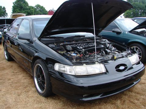 1993 Ford Taurus - A black sedan with its hood open, revealing the engine compartment and aftermarket wheels.