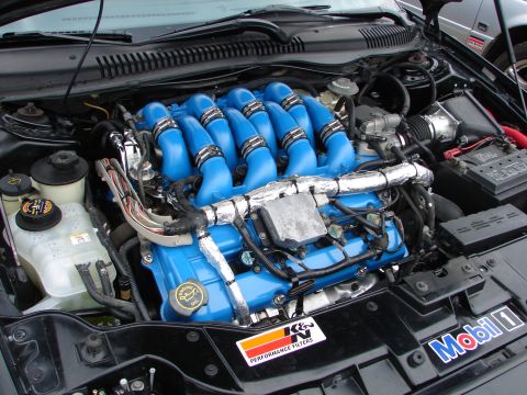 1993 Ford Taurus - Customized engine bay a vibrant blue intake manifold and performance filter branding.
