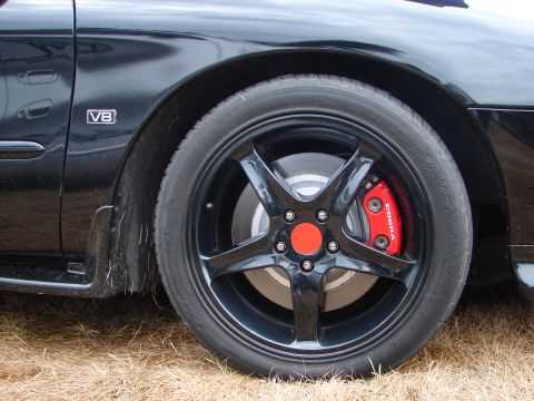 1993 Ford Taurus - Close-up of a black car wheel a red COBRA brake caliper and a V8 badge on the fender.