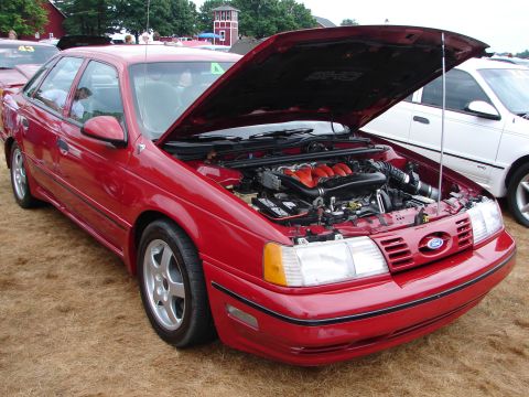 1993 Ford Taurus - A red 1993 Ford Taurus SHO is displayed with its hood open, revealing the engine and intake system.