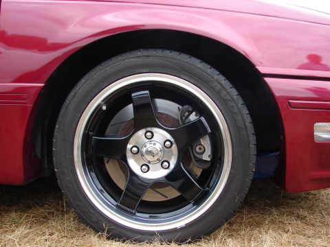 1993 Ford Taurus - Close-up of a red car's front wheel custom black five-spoke rims with a silver lip.