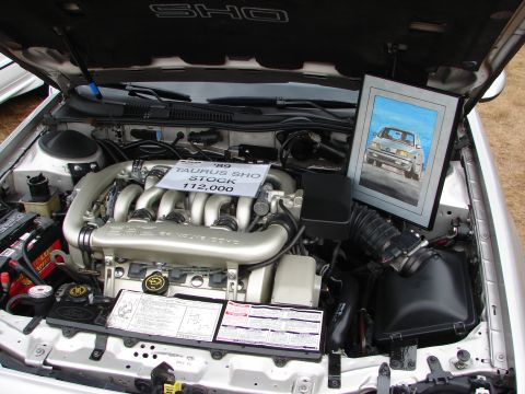 1993 Ford Taurus - The engine bay of a 1989 Ford Taurus SHO is displayed with a framed picture of the vehicle.