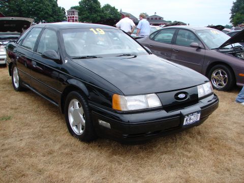 1993 Ford Taurus - This black 1993 Ford Taurus sedan is shown at a car show, displaying a yellow competition number on its windshield.