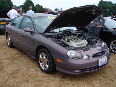 1993 Ford Taurus - Purple Ford Taurus at a car show, hood open to display its V8 engine. Another car is visible to the right.