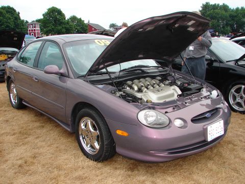 1993 Ford Taurus - A purple sedan is displayed with its hood open, revealing the engine, at an outdoor event.