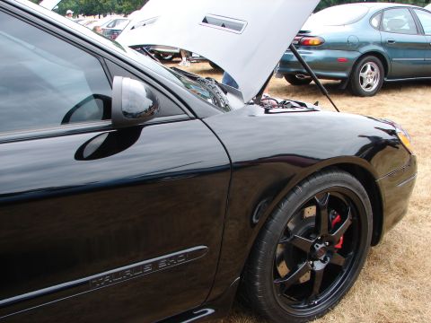 1993 Ford Taurus - Black car with hood open, "TAURUS SHO" badge visible on door. Green car in background.