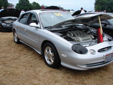 1993 Ford Taurus - Silver sedan's engine bay is open at a car show, with a '99 SF SHO' license plate visible.