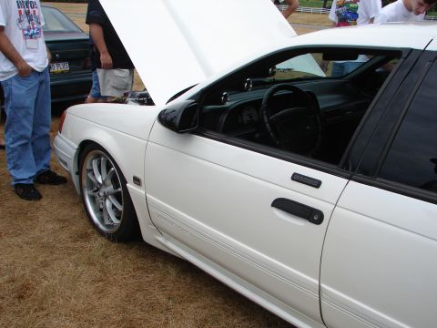 1993 Ford Taurus - A white 1993 Ford Taurus sedan is displayed with its hood open, revealing the interior and driver's side door.
