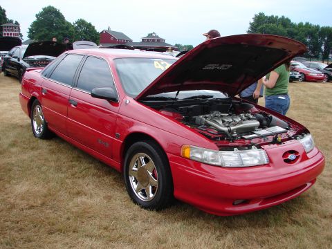 1993 Ford Taurus - A red 1993 Ford Taurus SHO is displayed with its hood open at an outdoor car show.