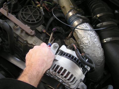 2000 Ford Excursion - Close-up of an engine bay, focusing on the alternator and surrounding components during a repair.