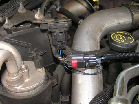 2000 Ford Excursion - A close-up view of engine components, including sensors, wiring, and large metal pipes.
