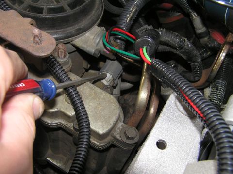 2000 Ford Excursion - Close-up view of a vehicle's engine bay, showing various wires and a hand holding a screwdriver.