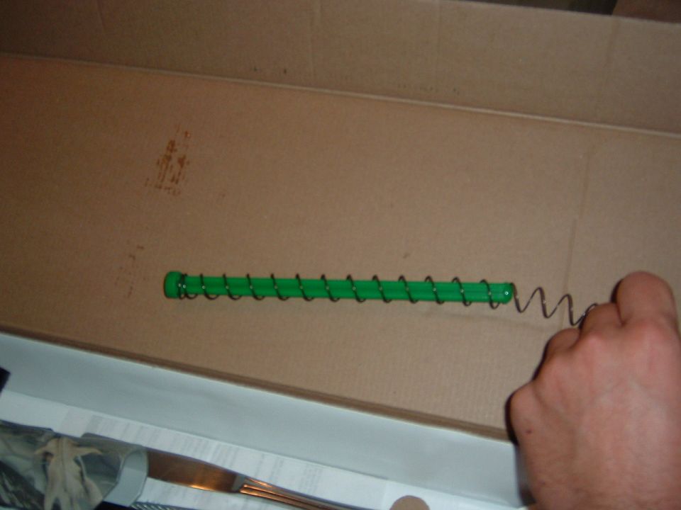 Gun magazine spring with green follower in a cardboard box