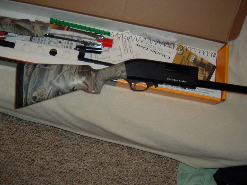 Shotgun with camouflage stock and black receiver labeled Charles Daly