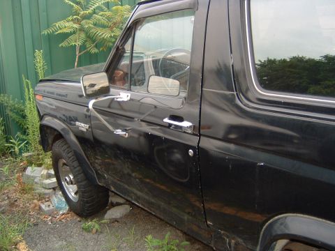 1986 Ford Bronco - This black 1980s Ford Bronco is shown from the side, revealing its door and fender details.