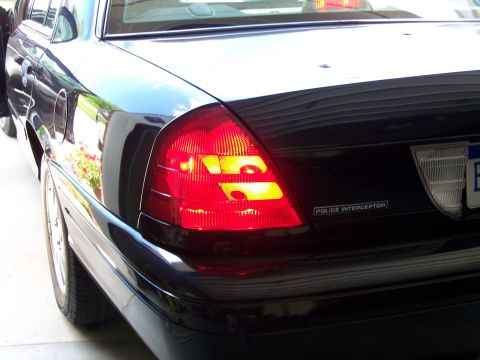 2003 Ford Crown Victoria - Rear view of a black 2003 Ford Crown Victoria Police Interceptor, showing its distinctive taillights and badging.