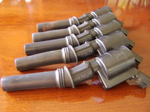 1996 Mercury Grand Marquis - A group of Ford spark plug wires are laid out on a wooden table. The Ford logo is visible on some of the wires.