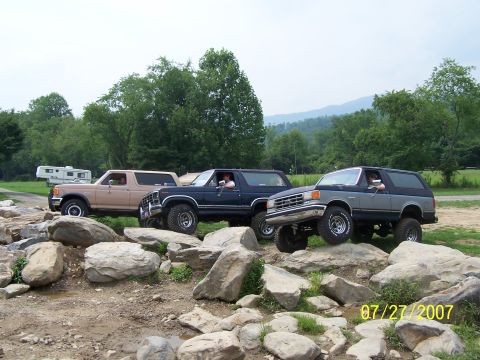 1979 Ford F-150 - Three Ford Broncos tackle a challenging rocky terrain on a sunny day.