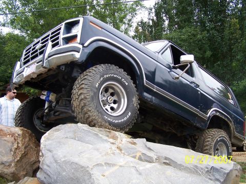 1979 Ford F-150 - This dark blue SUV, likely a 1978 model, navigates a rocky obstacle course with its large off-road tires.