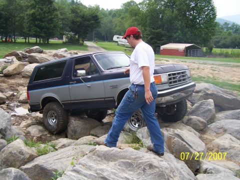 1979 Ford F-150 - A man walks beside a Ford Bronco as it navigates a rocky obstacle course.
