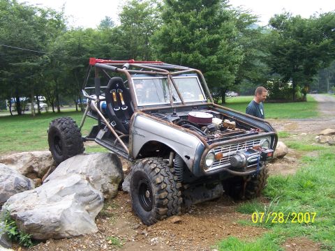 1979 Ford F-150 - Customized off-road vehicle with extensive roll cage and exposed engine, navigating rocky terrain.