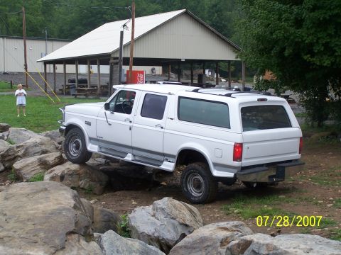 1979 Ford F-150 - A white extended cab pickup truck with a camper shell navigates a rocky terrain.