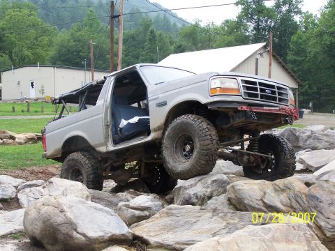 1979 Ford F-150 - A modified Ford Bronco is shown off-roading over large rocks on a sunny day.