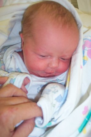 1966 Ford Galaxie - A newborn baby is held by a finger while wrapped in a blanket.
