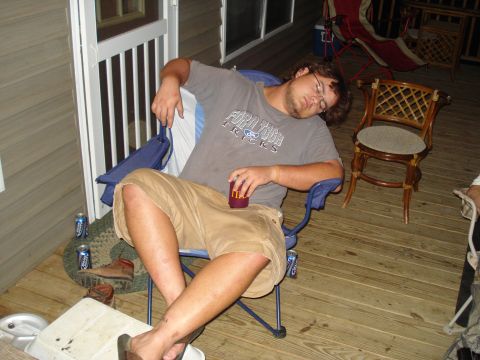 1984 Ford Bronco - A man sleeps in a chair on a porch with beer cans nearby.