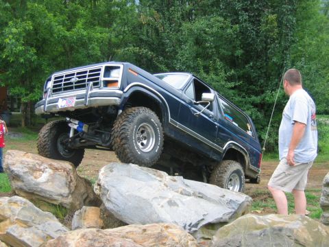 1992 Ford Mustang - A man watches a Ford Bronco navigate a rocky obstacle during an off-road event.
